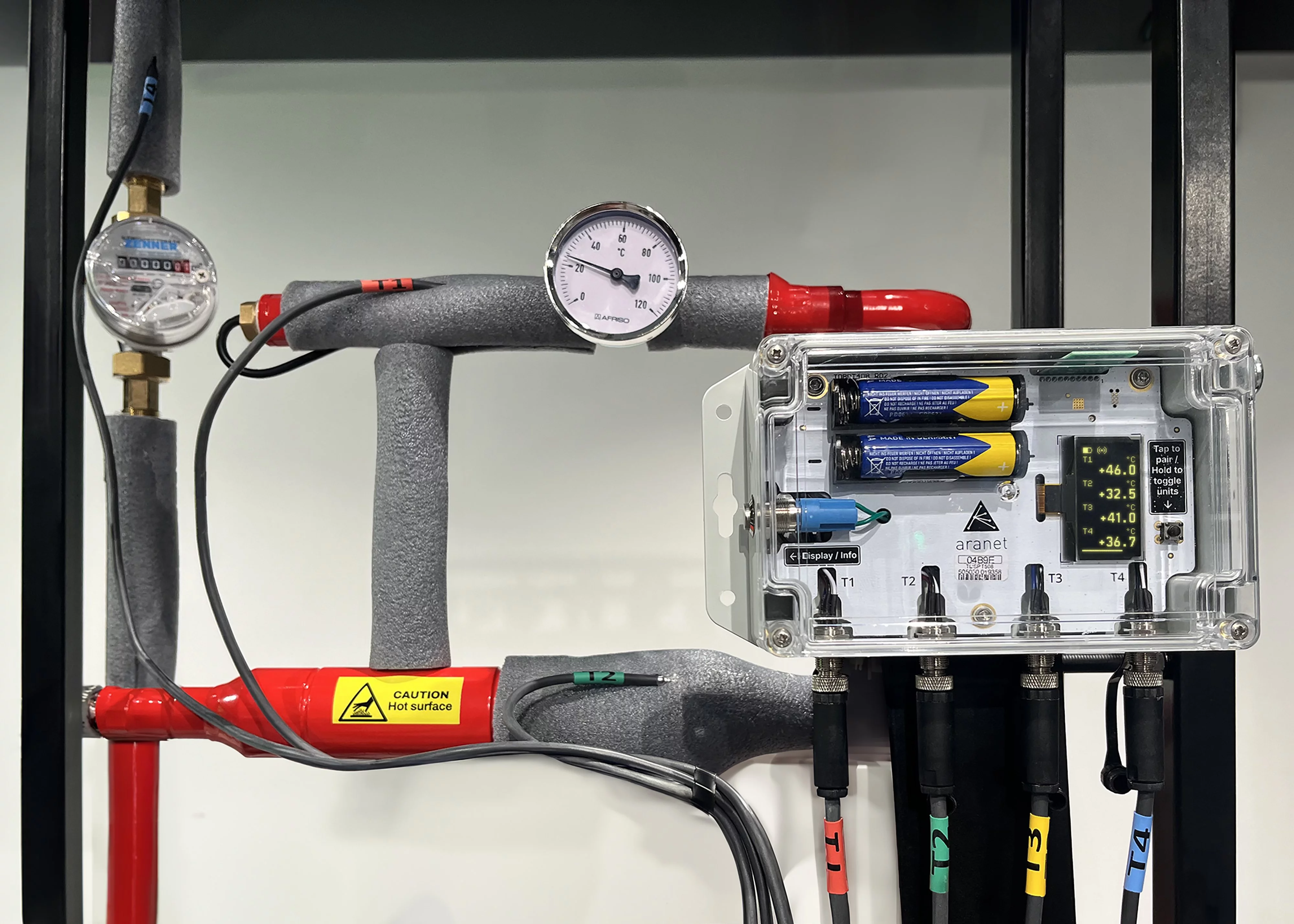 Das Funksensormodul Aranet 4-Kanal PT1000 misst Temperatur, angebracht an einem Heizungsrohr.